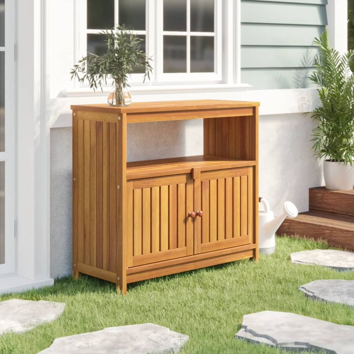 Holzschrank im Freien. Er hat zwei Türen, ein offenes Regal und eine Vase oben. Grünes Gras und Steine im Vordergrund.