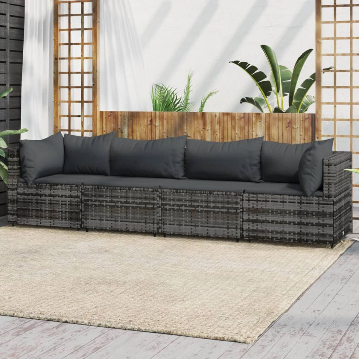 Graues Rattansofa mit grauen Kissen auf beigem Teppich, im Freien.