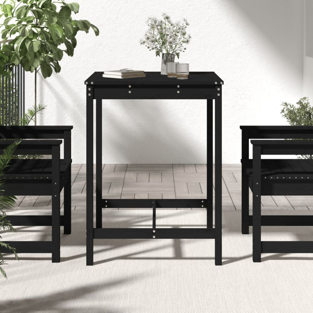 Schwarzes Outdoor-Tischset mit zwei Stühlen, weißer Wandhintergrund, mit Blumen.