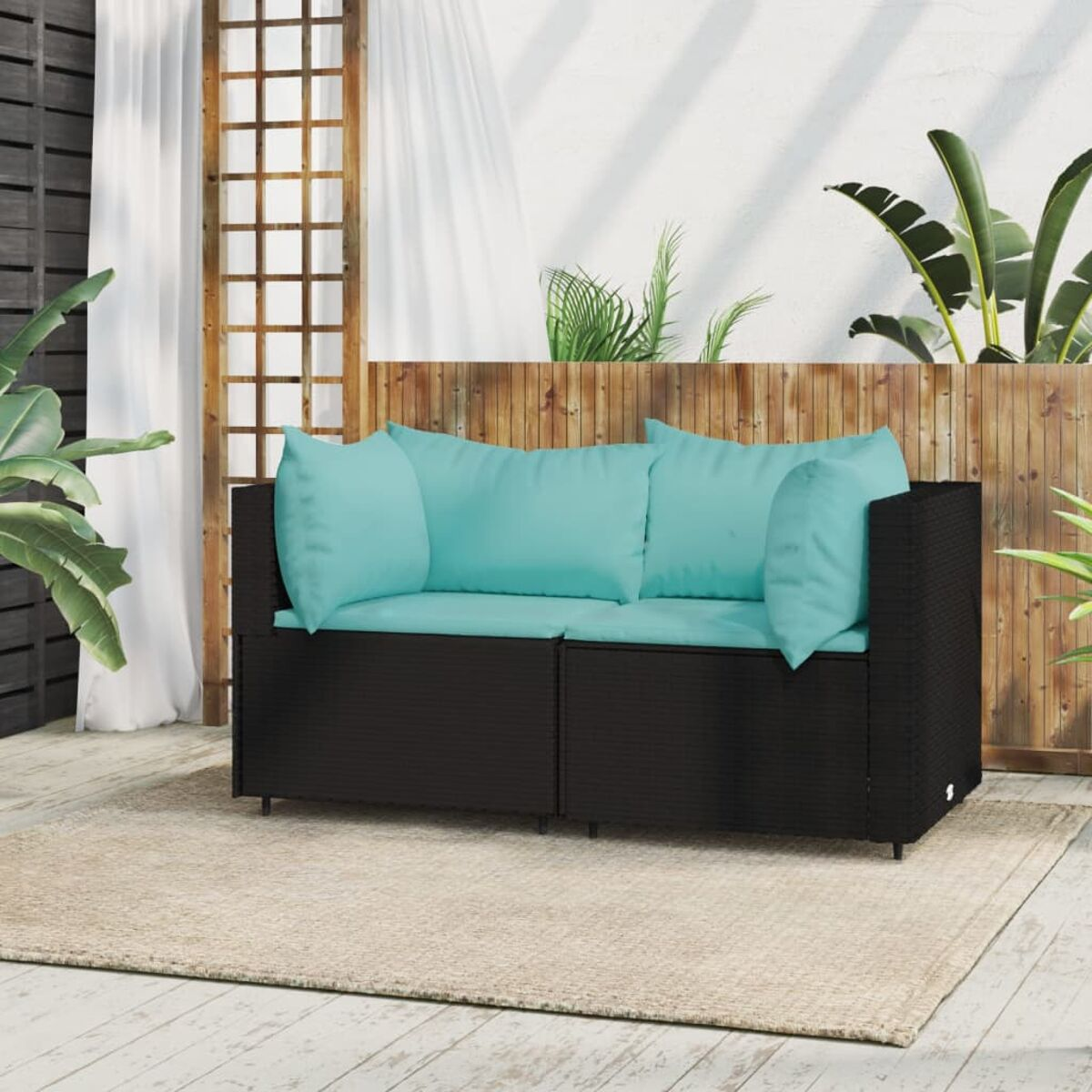 Ein schwarzes Outdoor-Sofa mit blauen Kissen auf einem beigen Teppich, mit weißen Vorhängen und grünem Hintergrund.