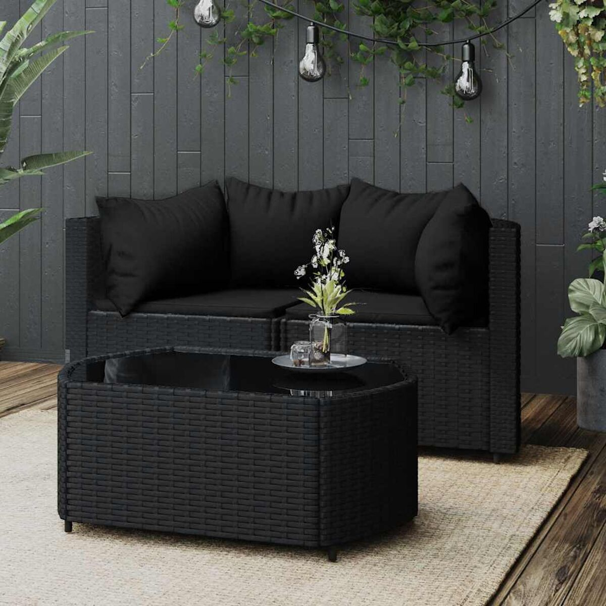 Schwarzes Outdoor-Möbelset aus Korbgeflecht mit Couchtisch und Kissen auf Holz.