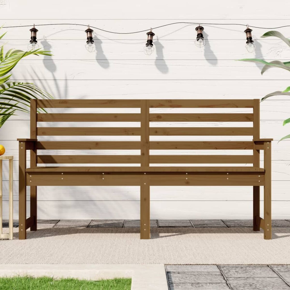 Braune Holzbank auf einer Terrasse. Weißer Wandhintergrund mit Hängelampen und Pflanzen.