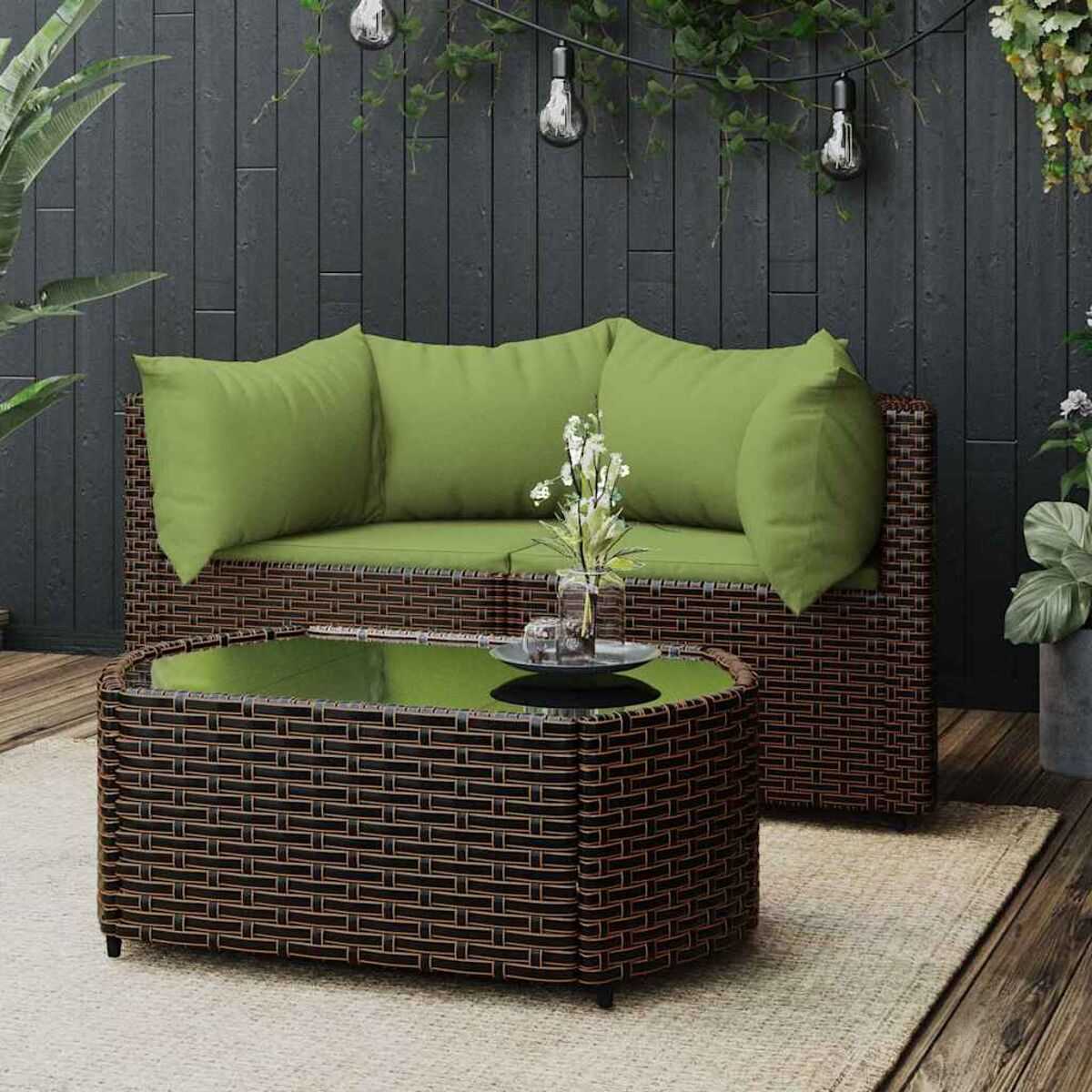 Rattansofa und Couchtisch. Grüne Kissen, Glasplatte, dunkelbrauner Rahmen, im Freien.