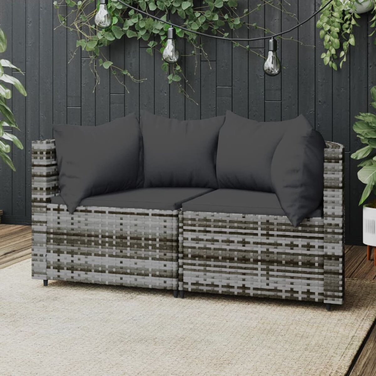 Graues Korbmöbel-Sofa mit dunkelgrauen Kissen auf weißem Hintergrund.