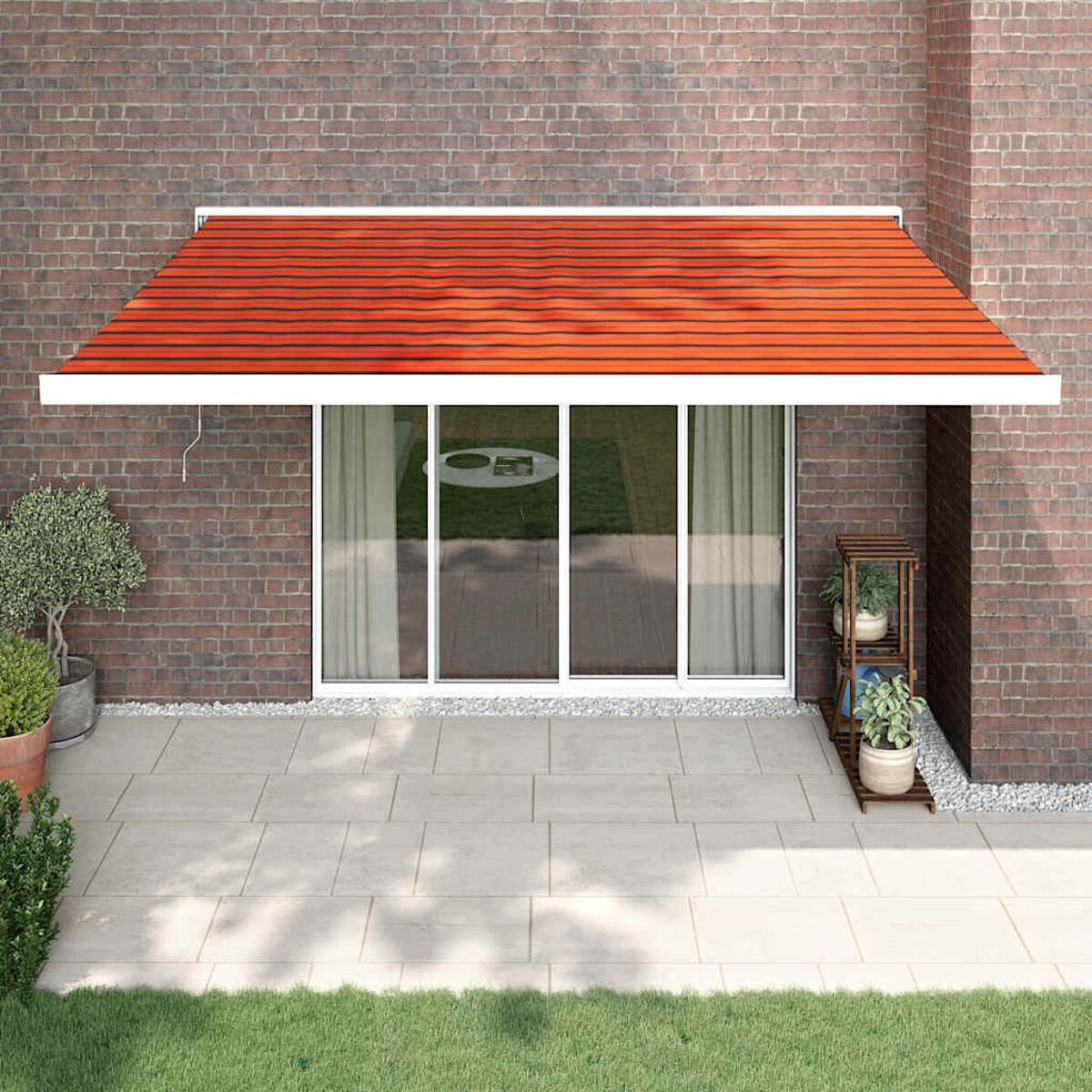 Hausfassade mit orangefarbener Markise, Glastüren und Steinterrasse.