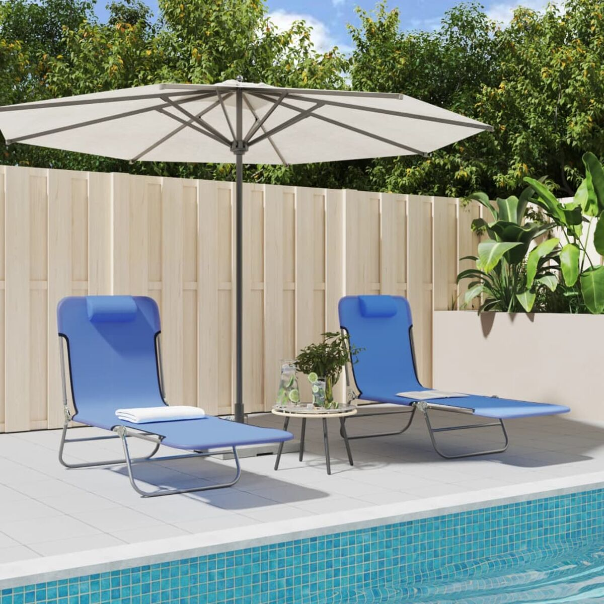 Zwei blaue Liegestühle in der Nähe eines Pools mit Schirm und Tisch.