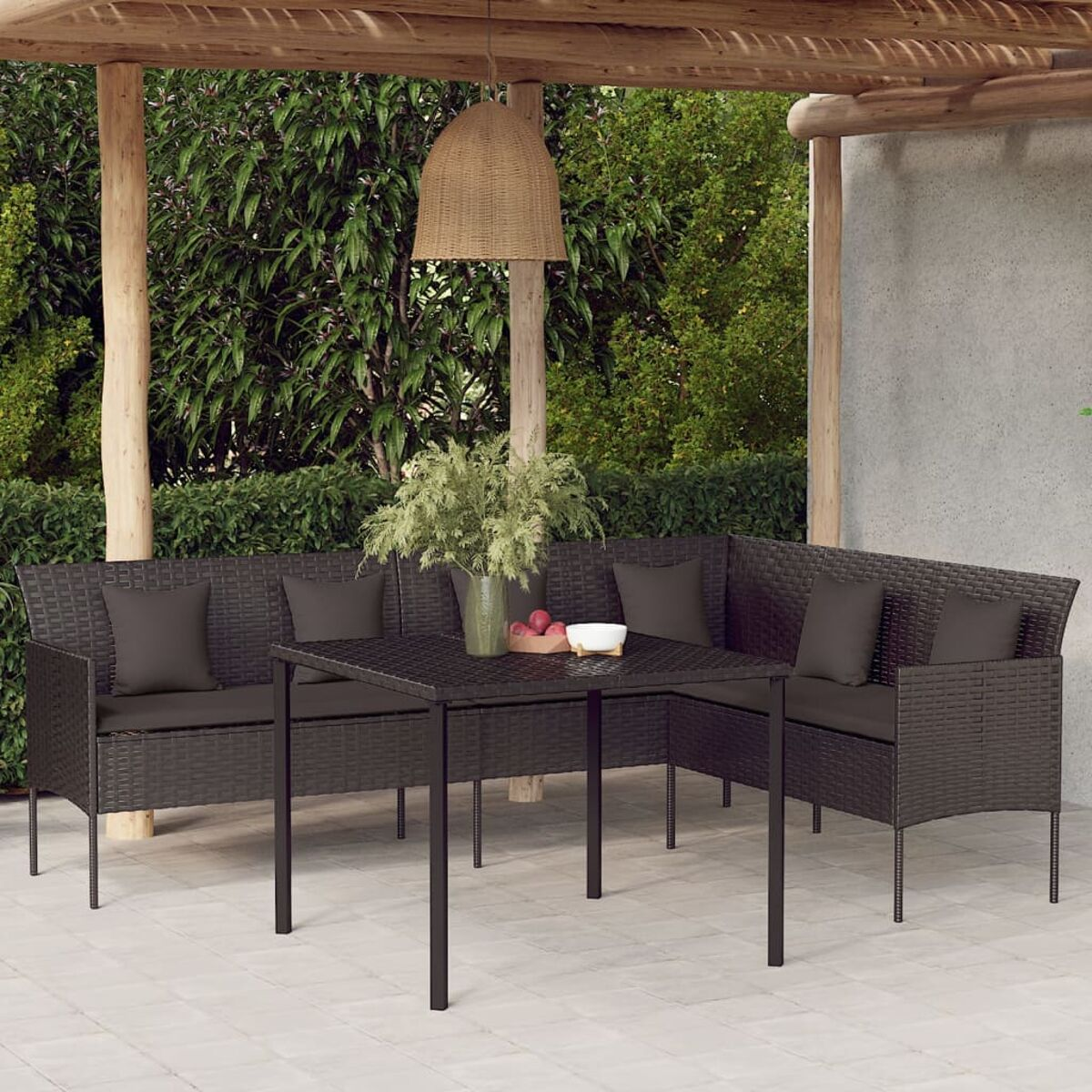Rattan-Gartenmöbel-Set mit Tisch und Kissen, unter einer Holzkonstruktion, mit Pflanzen.