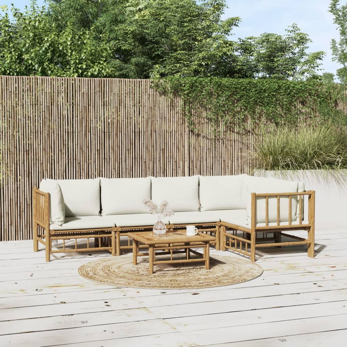 Ein hölzernes Outdoor-Sofa-Set mit cremefarbenen Kissen, einem runden Teppich und einem Bambuszaun im Hintergrund.