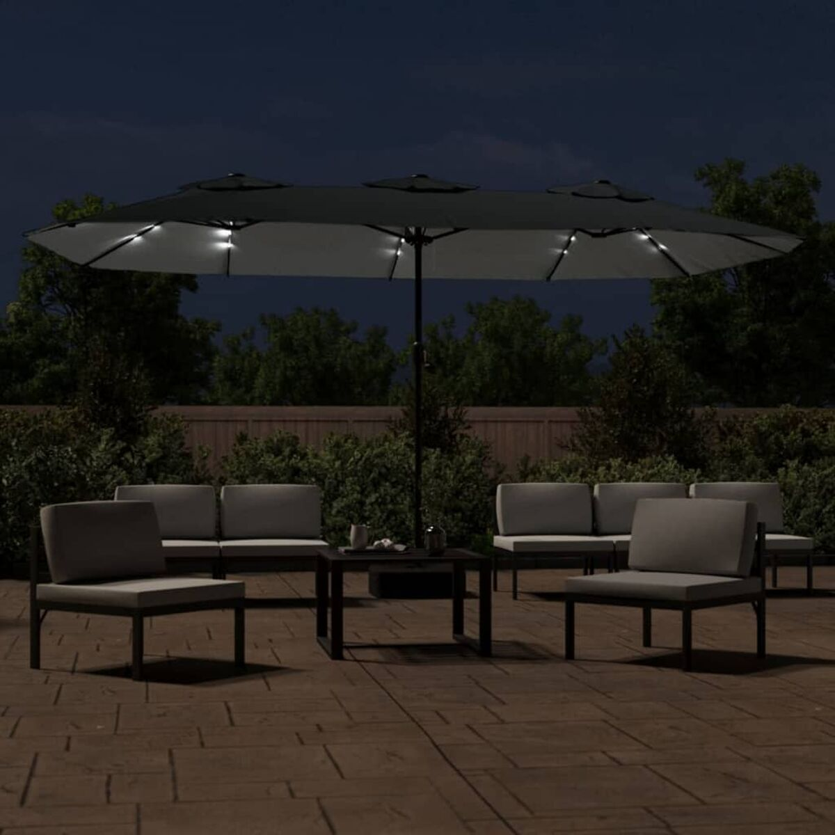 Nachtszenen mit Gartenmöbeln. Großer Schirm mit Lichtern, Sofa, Stühle und Tisch.