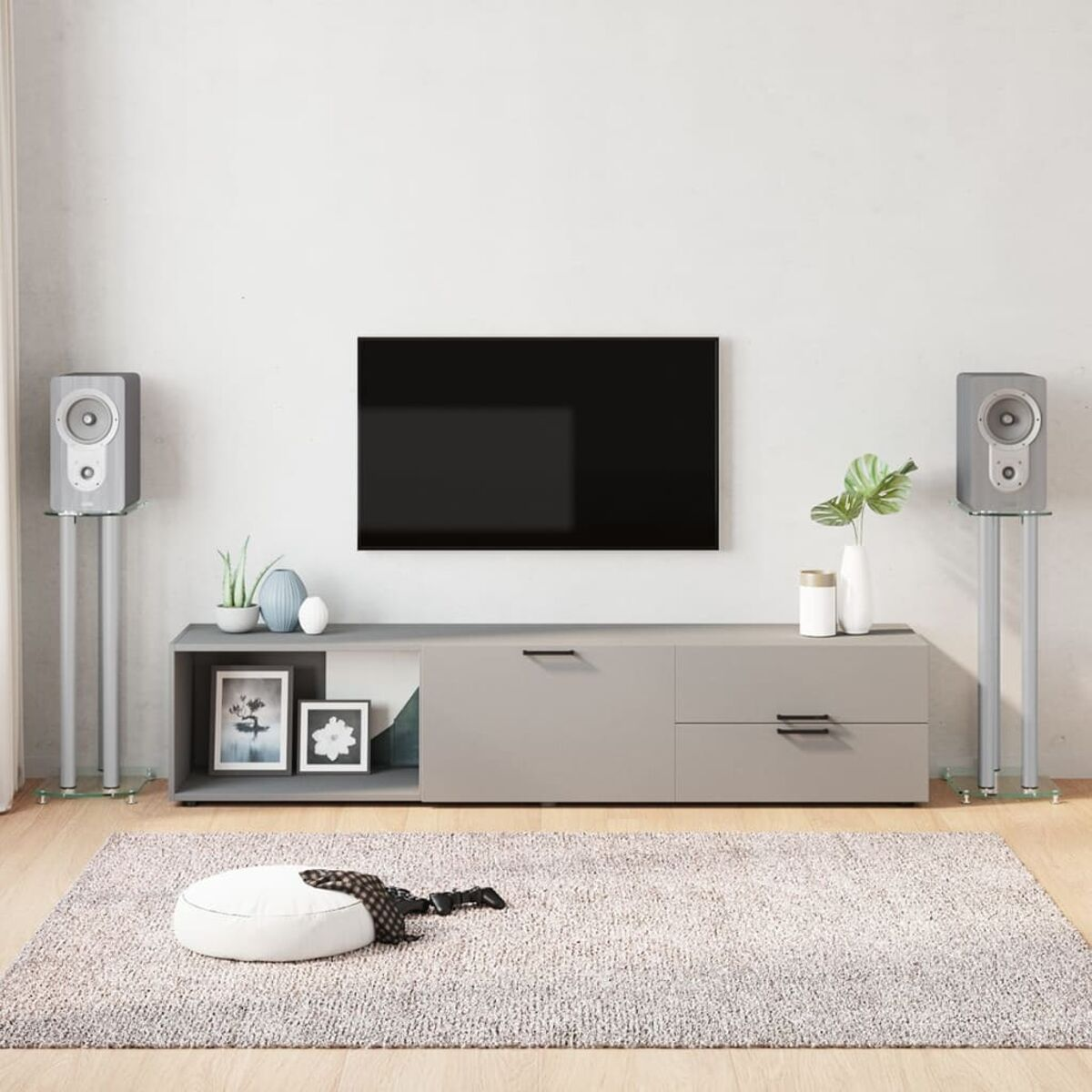 Wohnzimmer mit Fernseher, Lautsprechern, Bildern und Teppich.