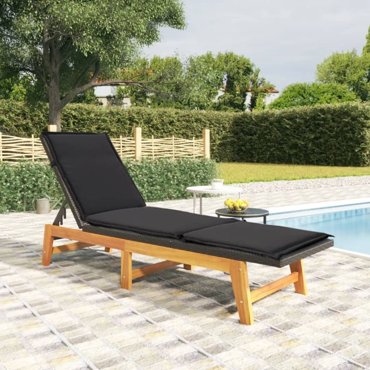 Chaiselongue aus Holz für den Außenbereich mit schwarzem Kissen auf einer Terrasse in Poolnähe.
