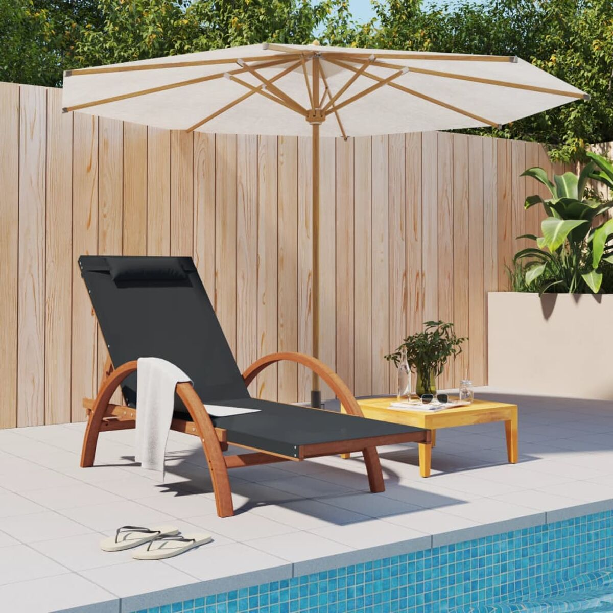 Liegestuhl, Sonnenschirm und kleiner Tisch am Pool. Holzzaun im Hintergrund.