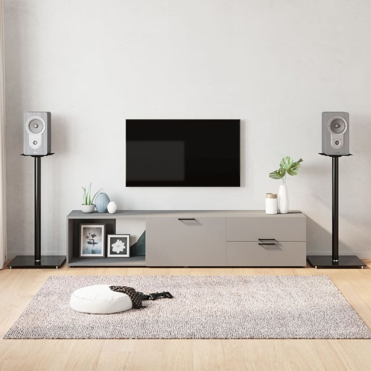 Wohnzimmer-Setup mit TV, Lautsprechern, grauem Schrank, Teppich und Dekoration.