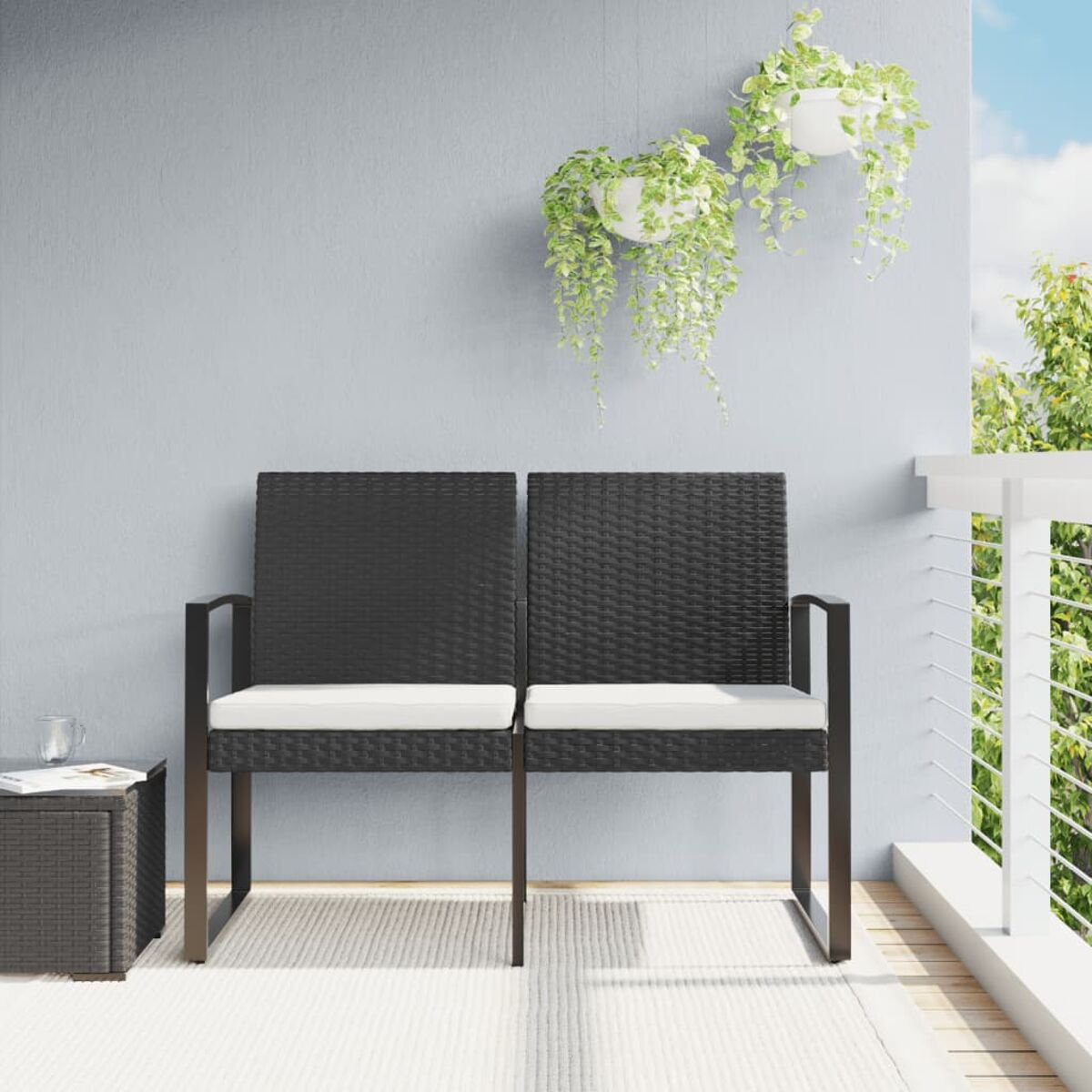 Zwei schwarze Webstühle mit weißen Kissen auf einem Deck mit hängenden Pflanzen.