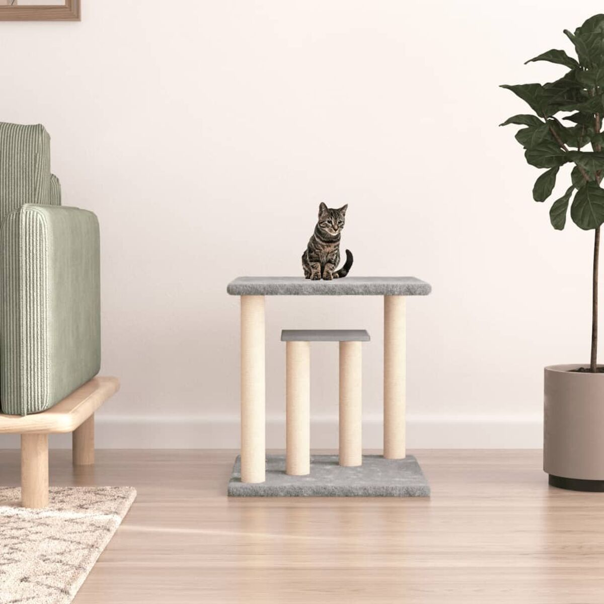 Eine Katze sitzt auf einem grauen Kratzbaum. Ein Sofa und eine Pflanze sind im Hintergrund.
