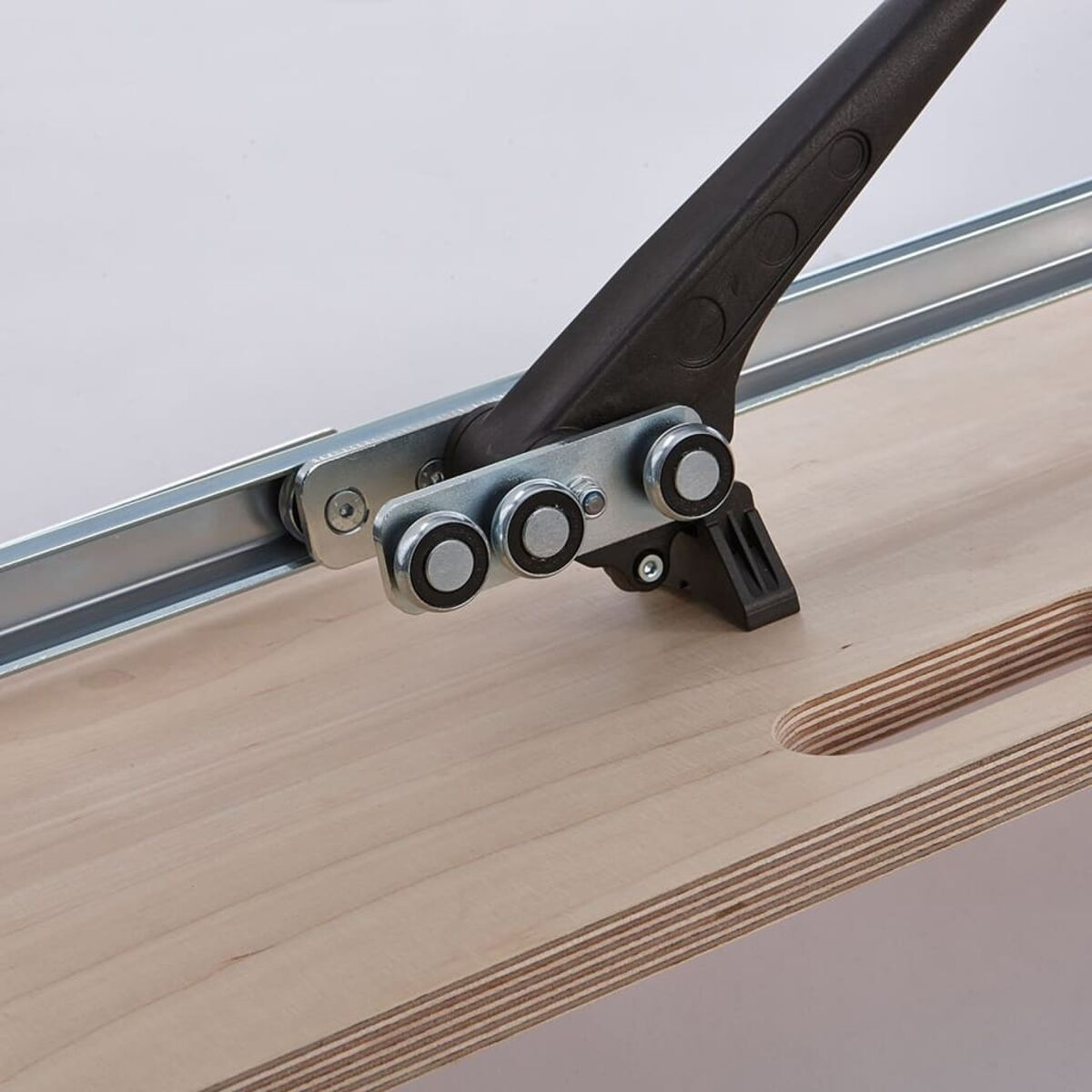 Una tavola di legno con un utensile da taglio attaccato, primo piano.