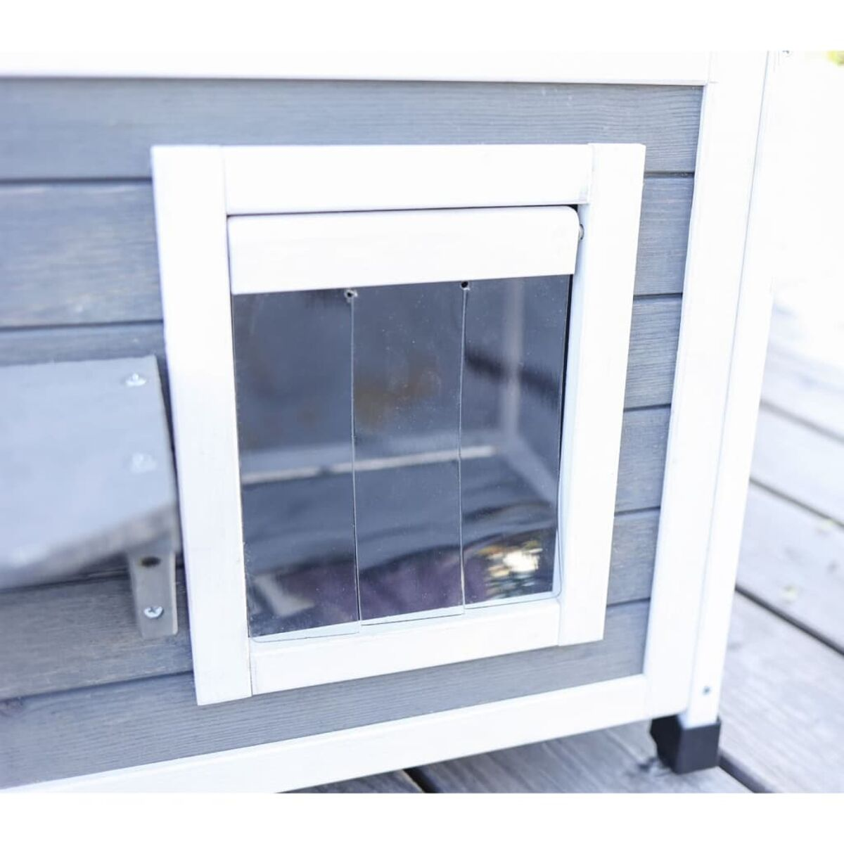 Detail des Hundehäuschens. Das Haus hat ein Fenster mit weißem Rahmen und eine graue Außenansicht.
