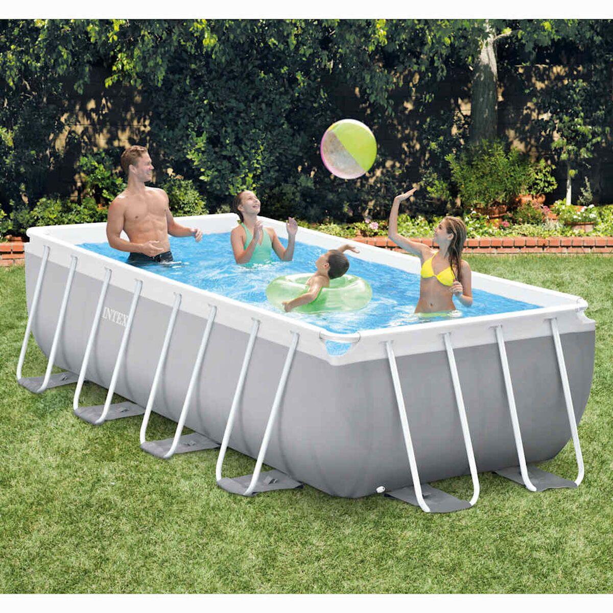 Menschen spielen in einem rechteckigen oberirdischen Pool in einem grasbewachsenen Garten.