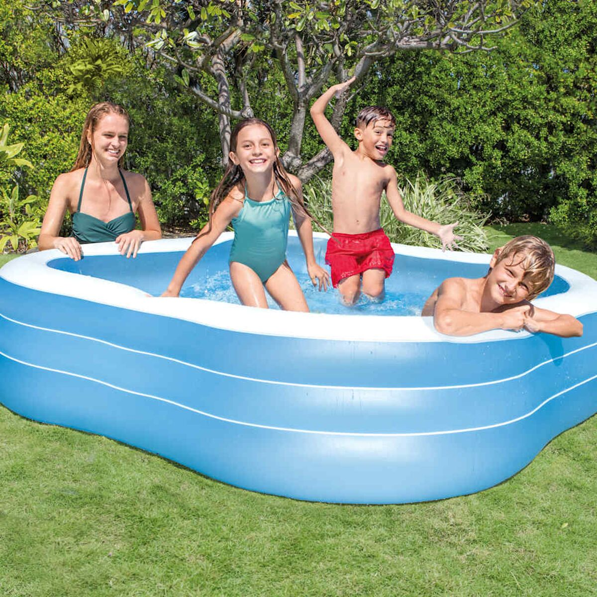 Kinder spielen in einem blauen aufblasbaren Pool. Ein Erwachsener beobachtet sie.