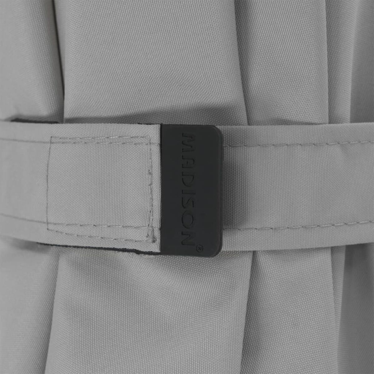 Close-up of a gray umbrella strap with the word 'MADISON' on it. The strap is fastened.