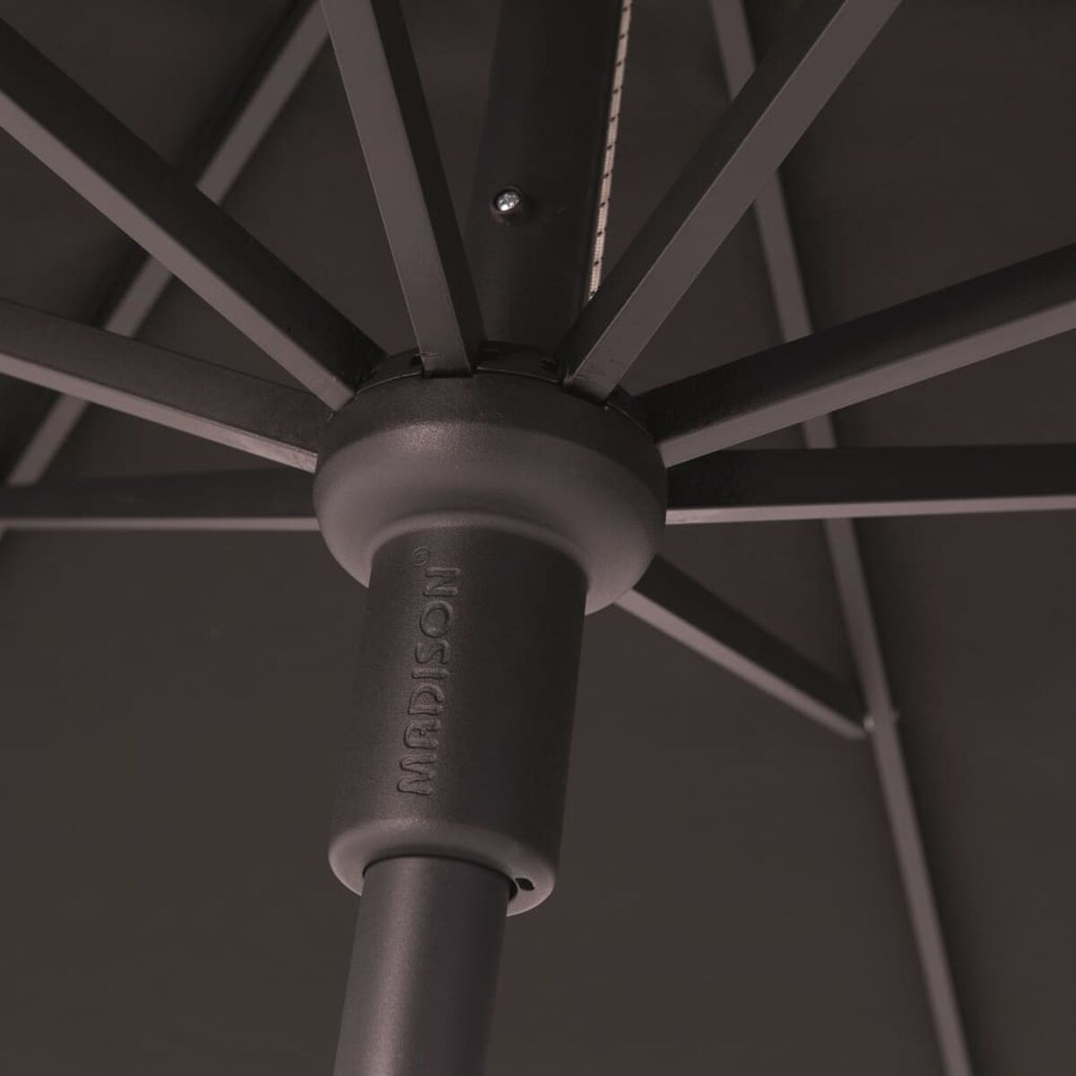 Close-up from underneath a dark brown umbrella with a metal frame, on a dark background.