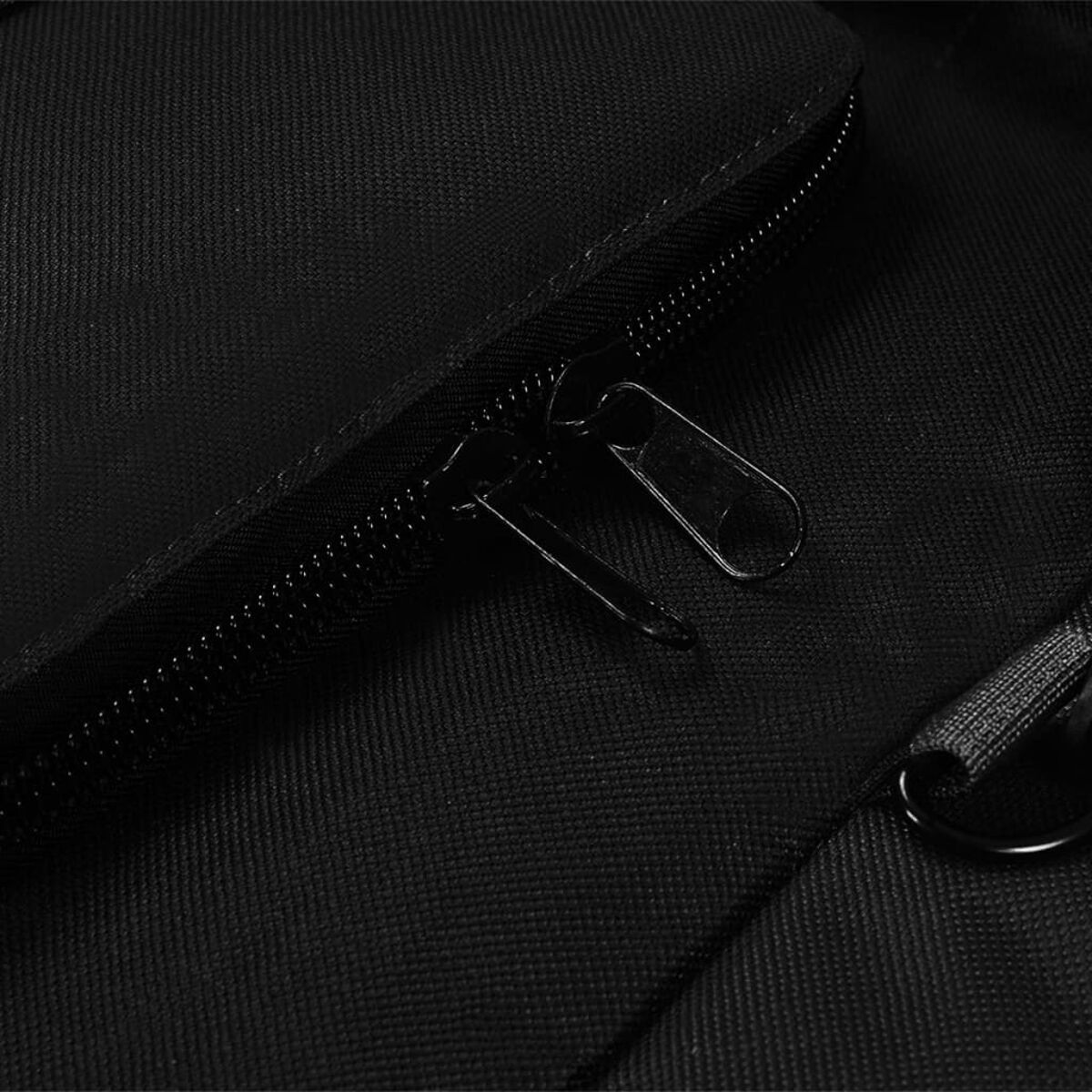 Nahaufnahme eines schwarzen Reißverschlusses auf schwarzem Stoff, der Reißverschluss ist geöffnet.