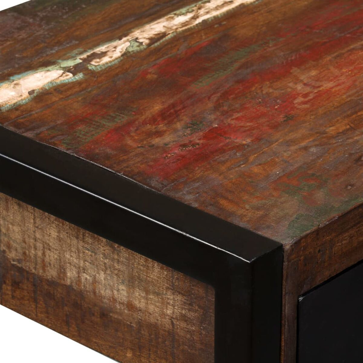 Nahaufnahme einer verwitterten Holztischecke. Das Holz hat mehrere Farben und einen schwarzen Metallrand.