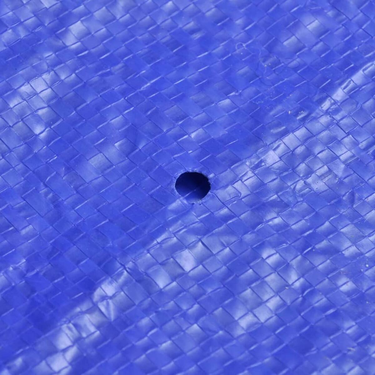 Nahaufnahme einer blauen gewebten Plane mit einem Loch.