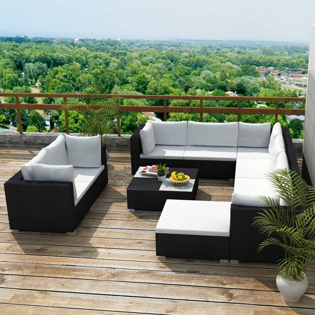 Ein Terrassen-Set mit schwarzen Korbmöbeln, weißen Kissen und einem Holzdeck.