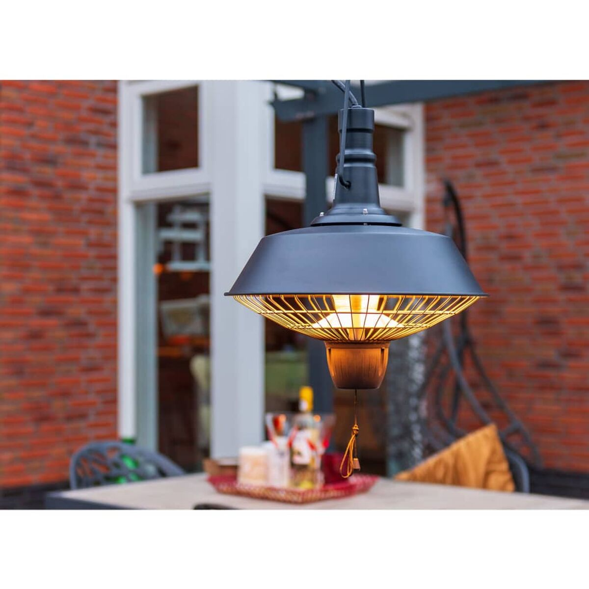 Zwarte buitenlamp die hangt met uitzicht op een bakstenen gebouw.
