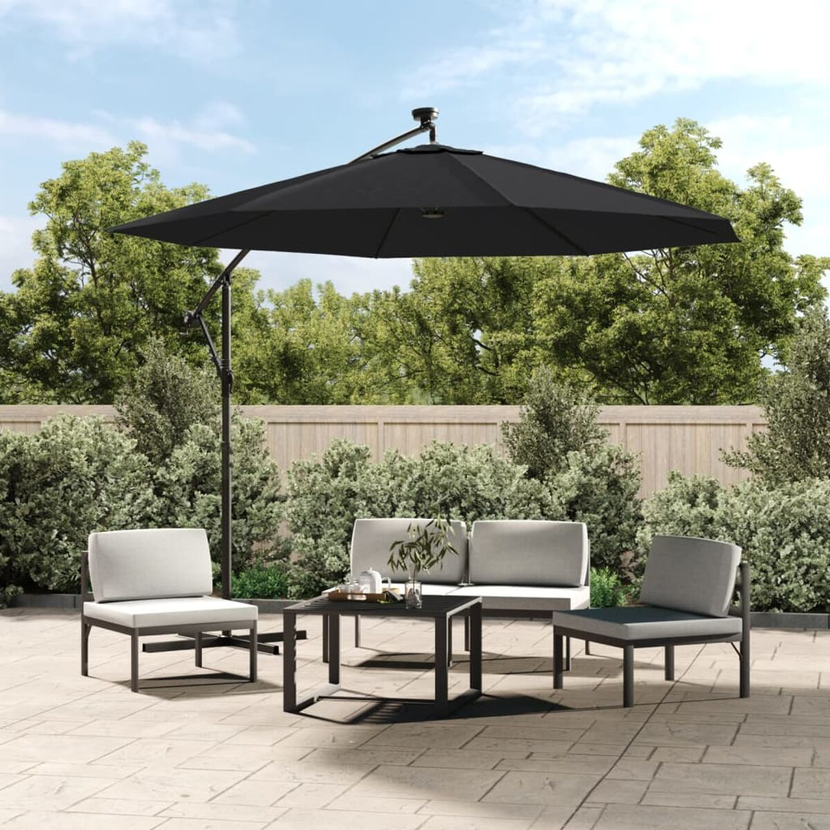 Terrassenmöbel-Set im Freien mit Sonnenschirm, Stühlen und Tisch. Der Hintergrund ist ein Garten und Bäume.