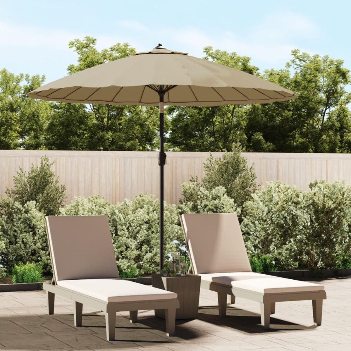 Zwei beige Liegestühle mit Sonnenschirm und Beistelltisch in einem Garten mit Bäumen und Holzzaun.