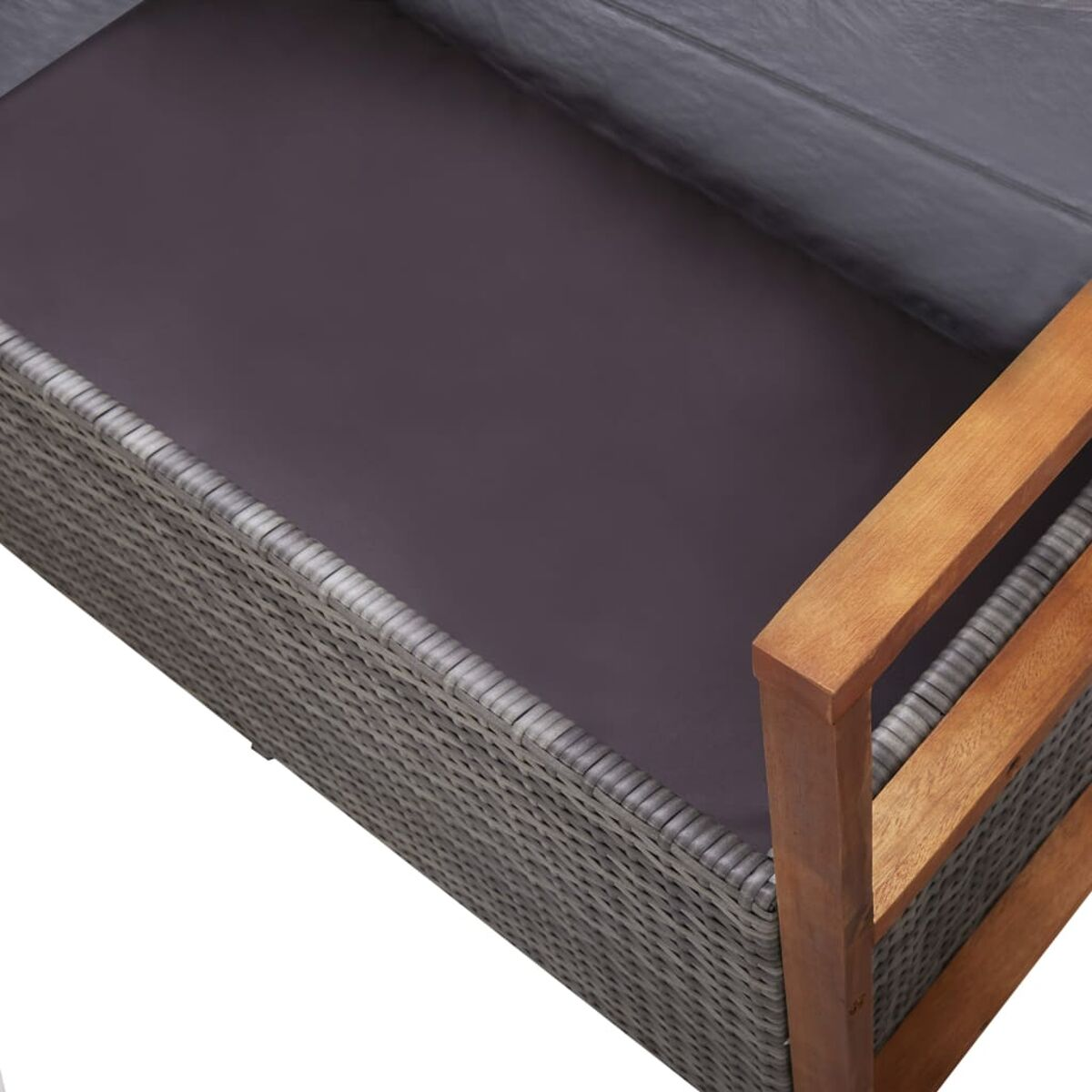 Nahaufnahme einer Ecke eines grauen Rattansofas. Der Sitz ist mit einem dunkelgrauen Kissen bedeckt. Die Armlehne ist aus Holz.