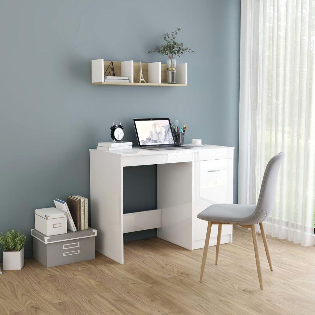 Weißer Schreibtisch mit Schubladen, Laptop, Büchern und Regal vor blauer Wand.