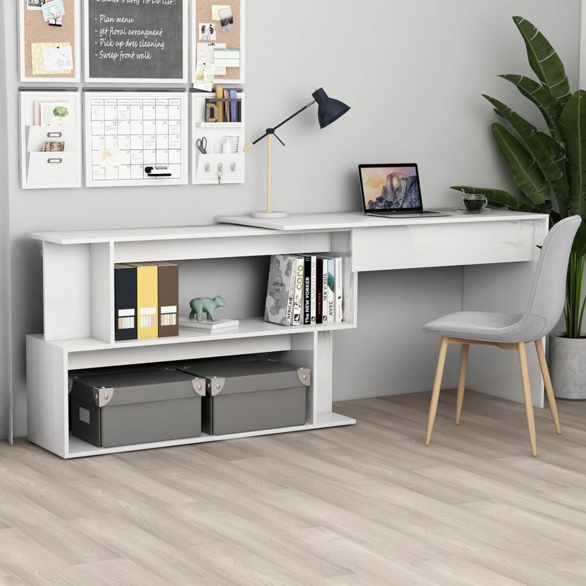 Weißer Schreibtisch mit Regalen, Laptop und Stuhl. Eine Wand mit Kalender und Notizen dahinter.