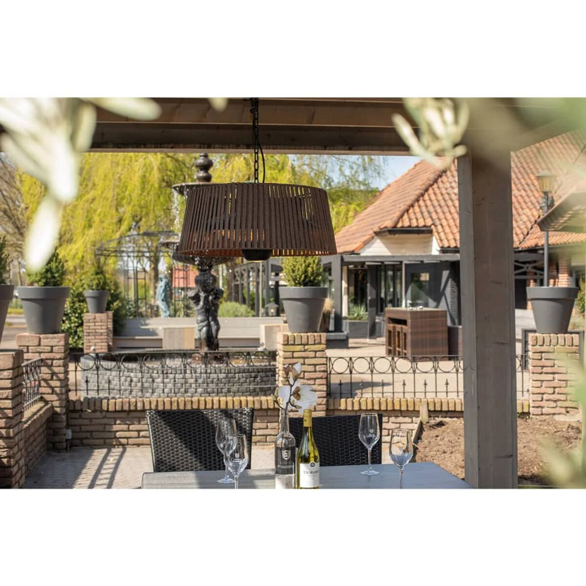 Ein Essbereich im Freien mit einer Hängelampe und einem gedeckten Tisch. Die Szene spielt in einem Garten.