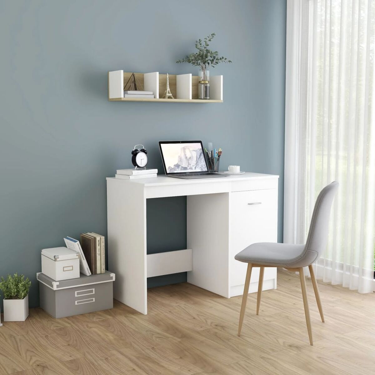Weißer Schreibtisch mit Laptop und Zubehör, blaue Wand im Hintergrund.