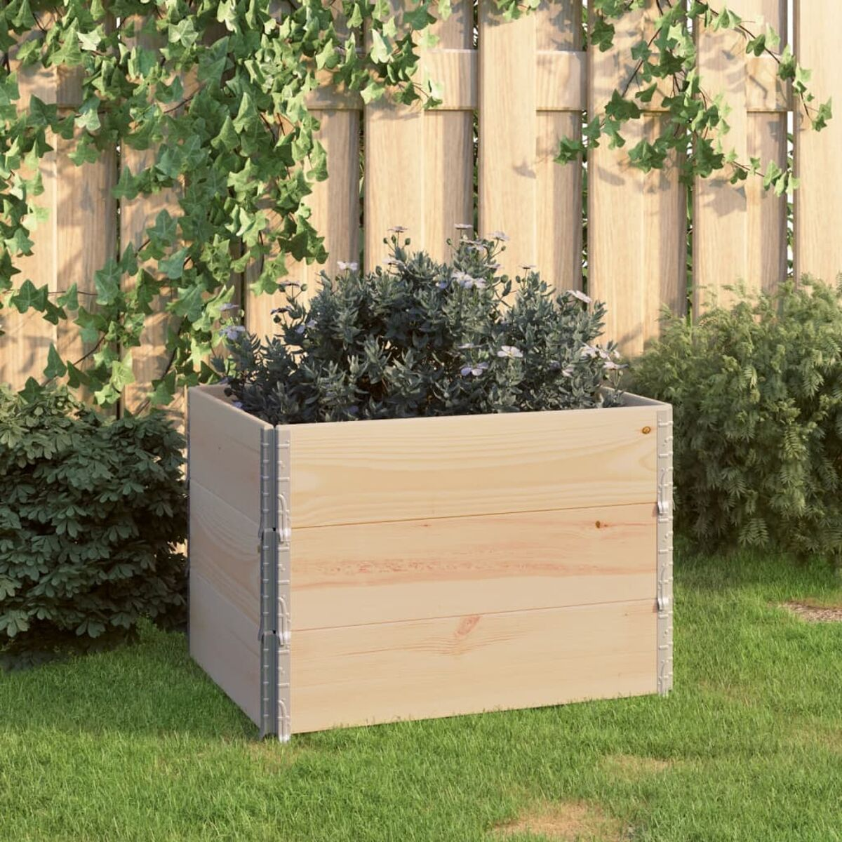 Ein Holzpflanzer mit einem Busch darin. Der Pflanzer befindet sich auf einer Rasenfläche. Der Hintergrund ist ein Holzzaun.