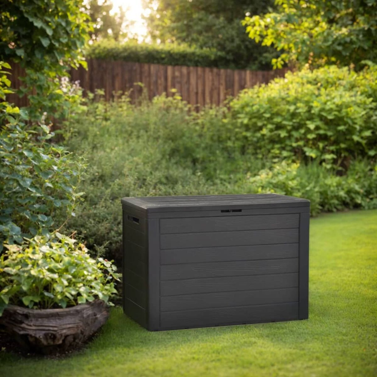 Schwarze Outdoor-Aufbewahrungsbox in einem Garten, umgeben von Grün und einem Holzzaun.