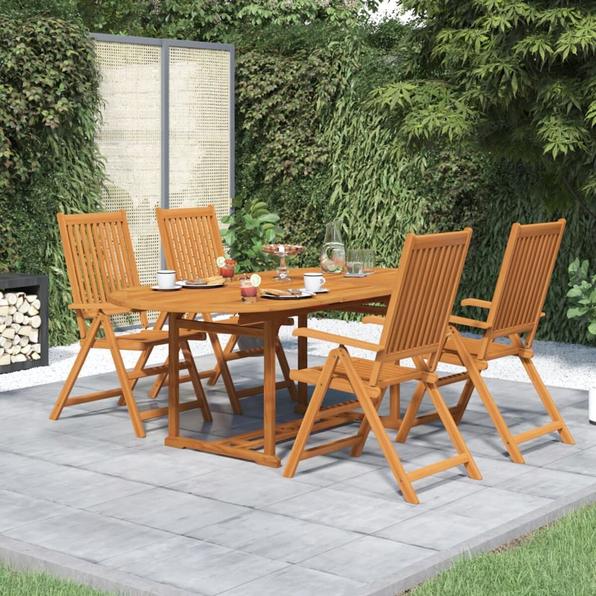 Ein hölzernes Ess-Set für den Außenbereich mit Tisch und vier Stühlen auf einer Terrasse. Grüne Büsche im Hintergrund.