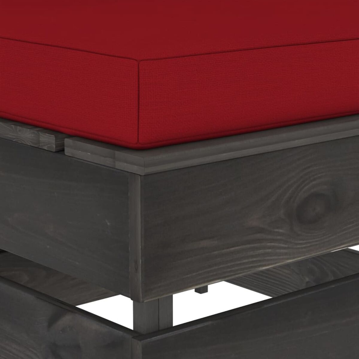 Nahaufnahme eines Holzpalettensofas mit rotem Kissen. Das Holz hat einen dunkelgrauen Anstrich.
