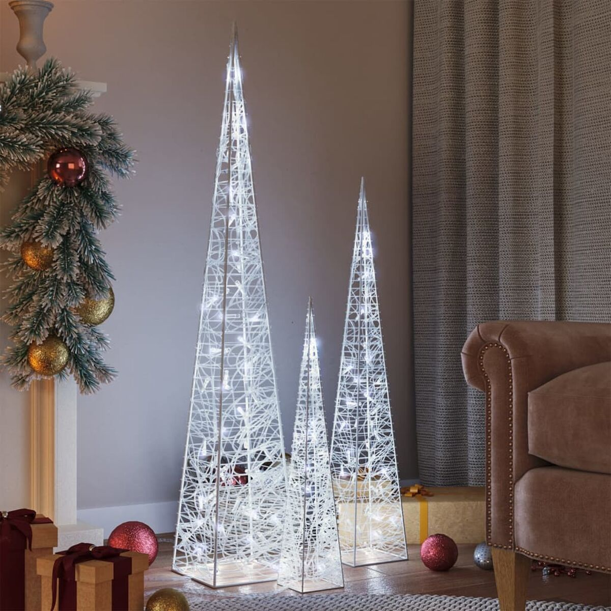 Drei weiße weihnachtsbaumförmige Lichter in verschiedenen Größen auf einem Holzboden an einer Wand.
