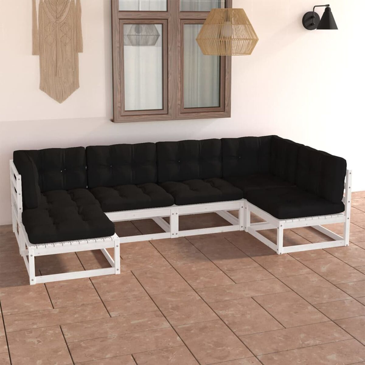 Weiß gerahmtes Outdoor-Sofa mit schwarzen Kissen. Neutrale Umgebung, Makramee-Wanddekor.