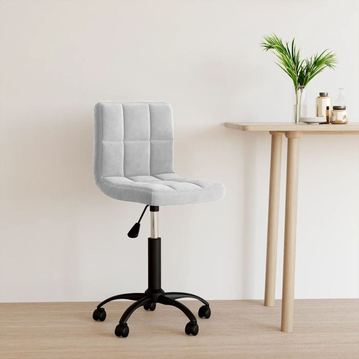 Weißer Bürostuhl mit schwarzem Gestell und Rollen. Ein Tisch und ein Blumentopf sind im Hintergrund.