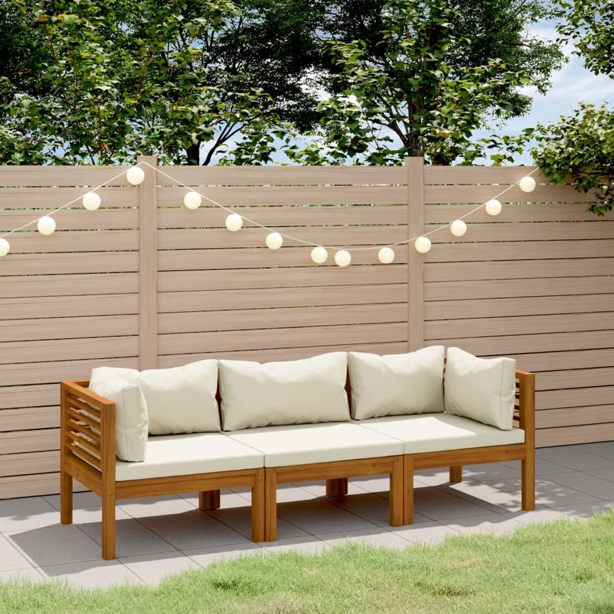 Outdoor-Holzsofa mit Kissen, auf einer Terrasse mit Lichterketten und Gras.