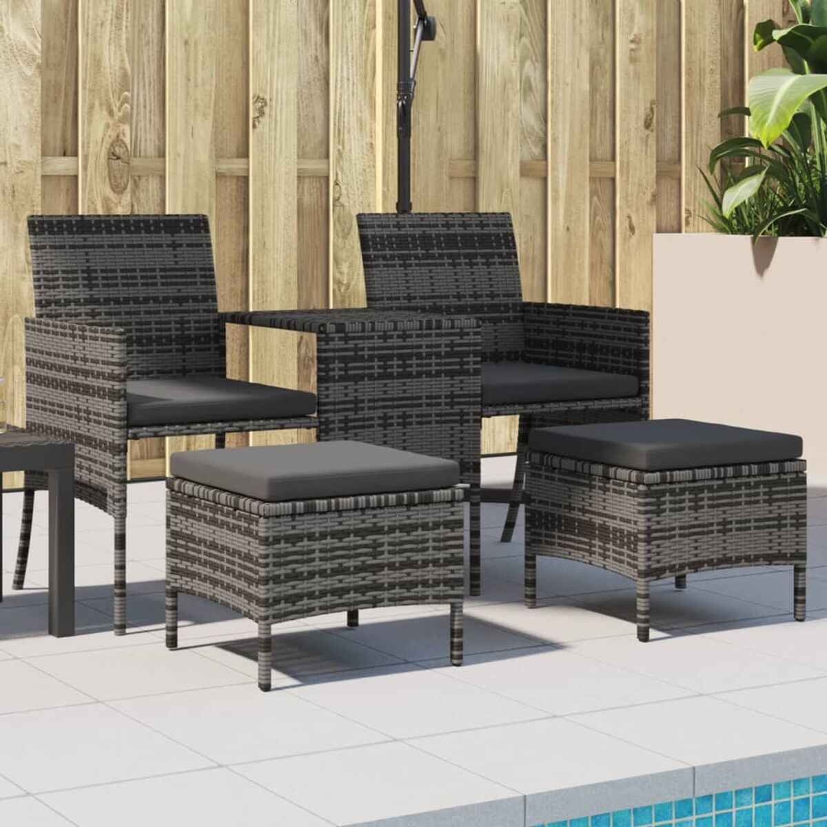 Sedie e pouf in vimini grigio scuro con cuscini neri. Recinzione in legno e piscina sullo sfondo.