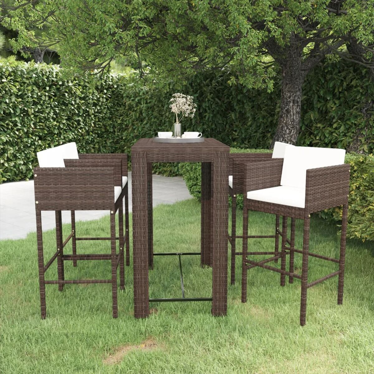 Essgruppe im Freien: braune Korbstühle, Tisch, weiße Kissen, in einem Garten mit Gras und Bäumen.