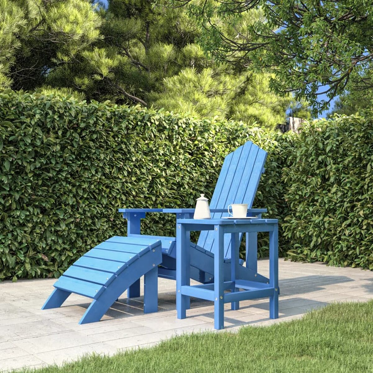 Blaues Adirondack-Stuhl-Set mit Beistelltisch und Fußstütze. Das Set befindet sich im Garten.