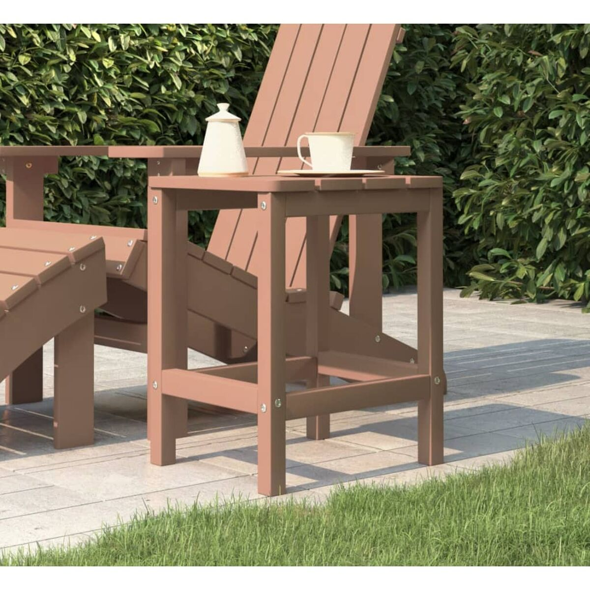 Ein kleiner brauner Tisch mit Zuckerdose und Tasse, in einer Gartenszene.