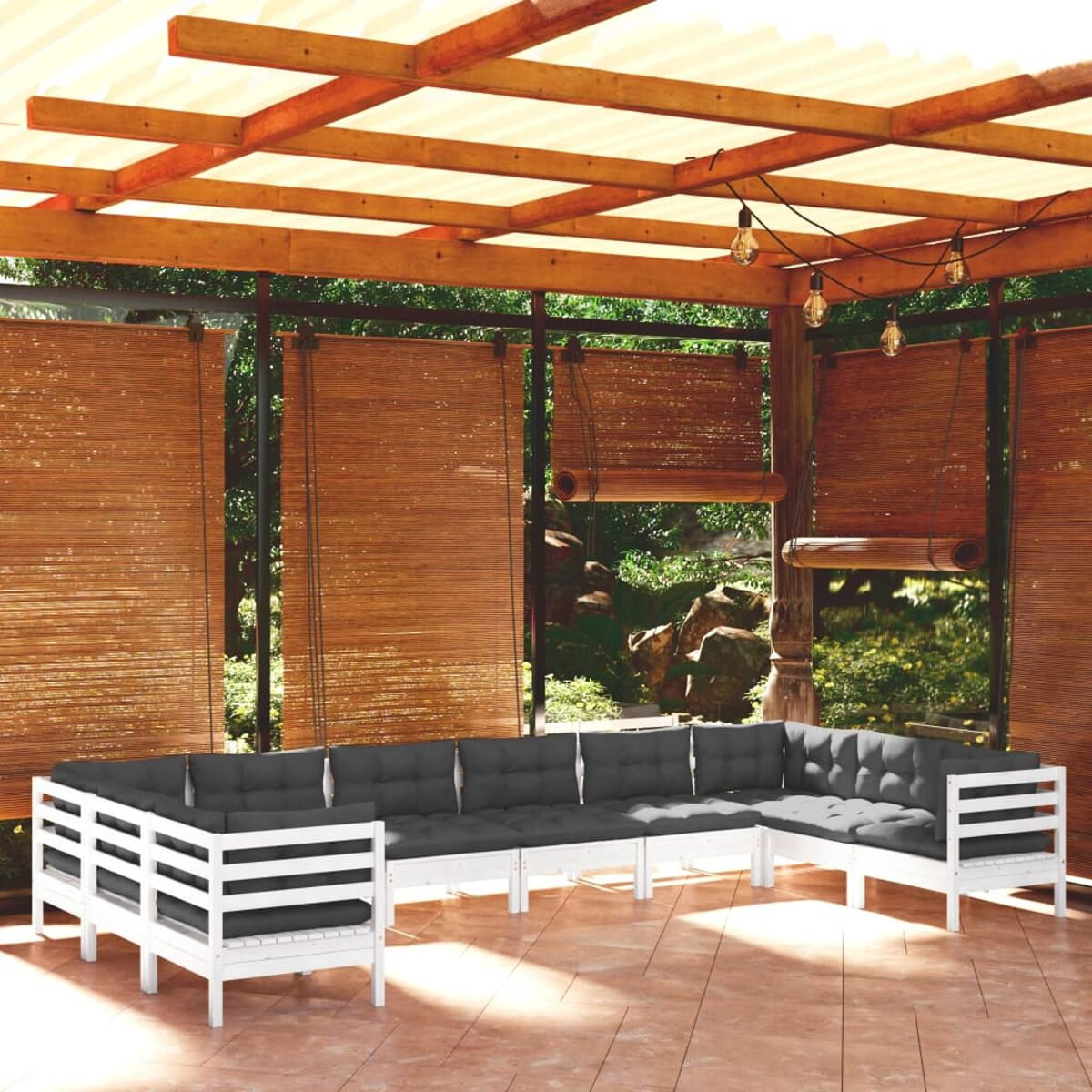 Weiße Outdoor-Sofagarnitur aus Holz mit grauen Kissen. Unter Holzpergola, mit Bambus-Sichtschutz.